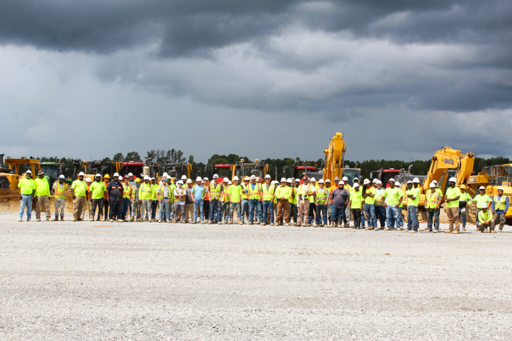 Workers posing in front of machines